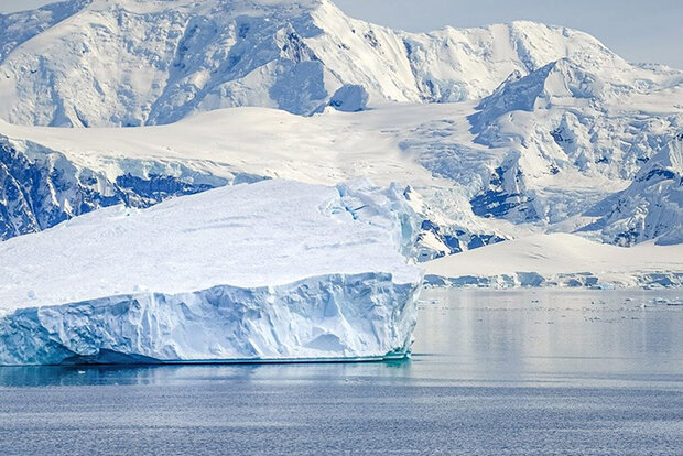 Iceberg in front of snowy mountains