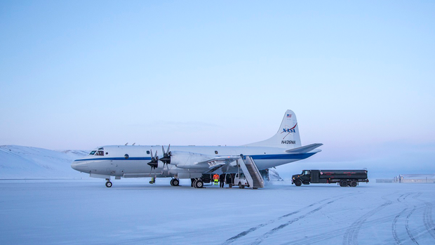 White airplane on icy ground with truck